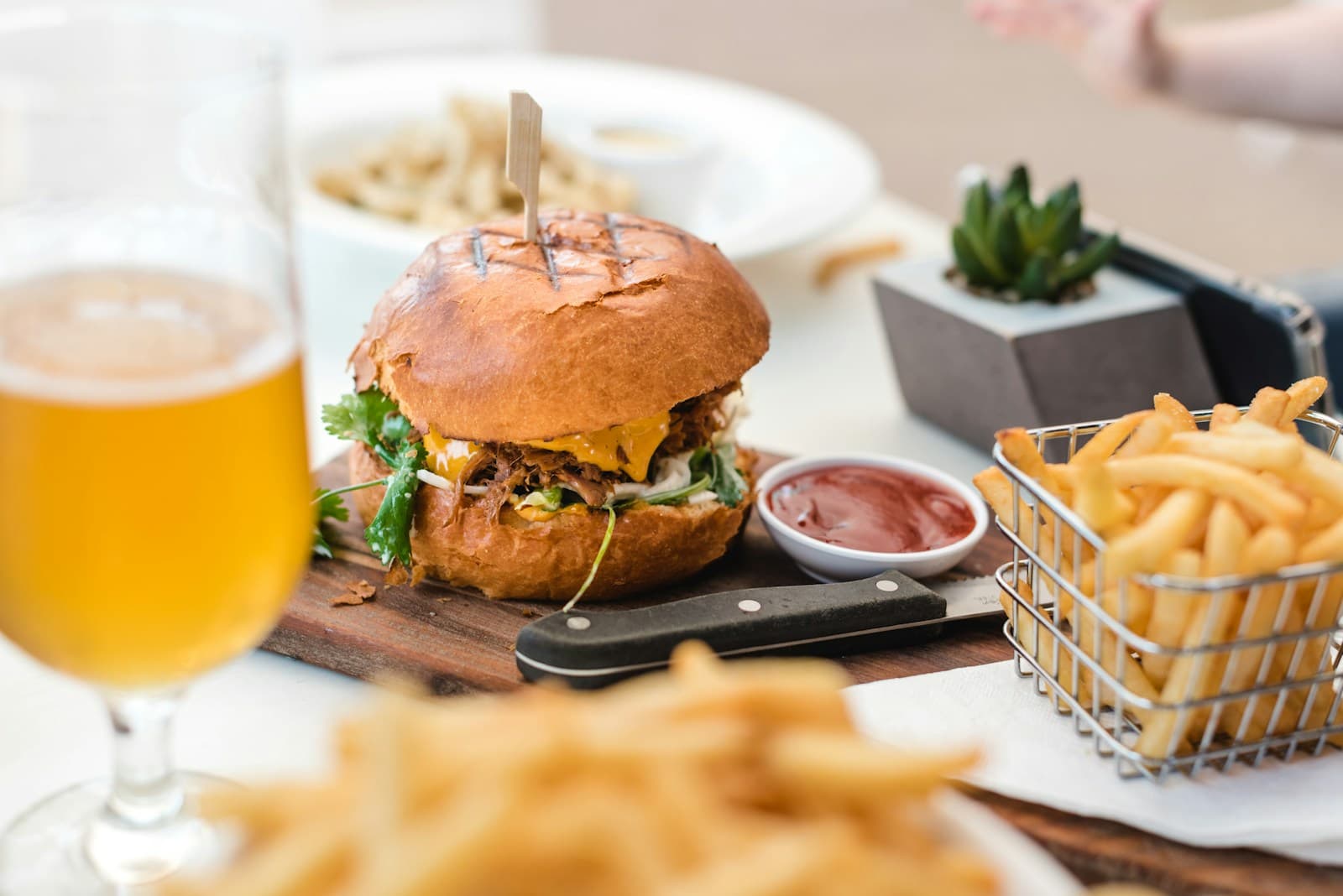 A burger and fries with a glass of beer
