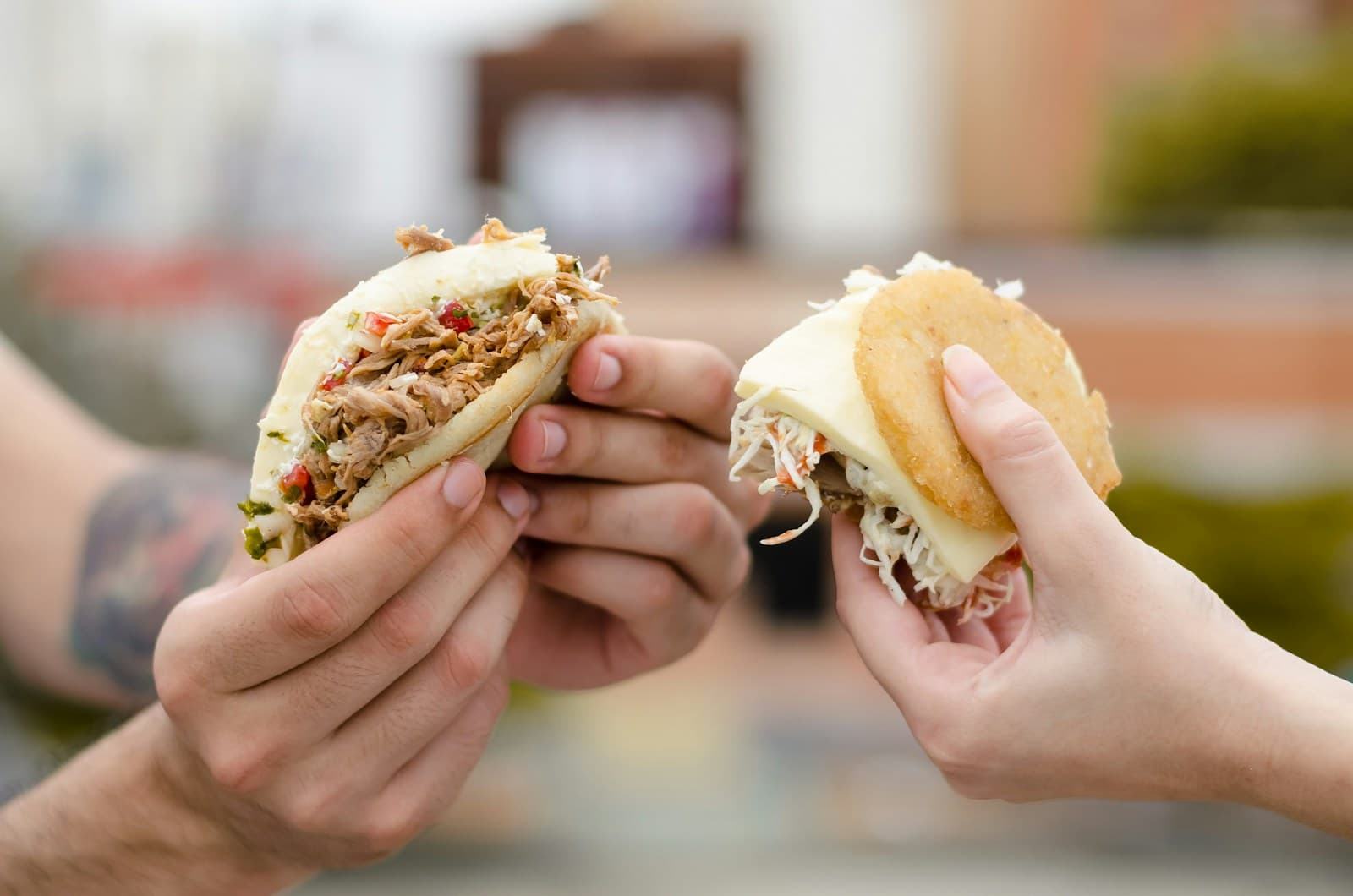 Two people holding stuffed arepas